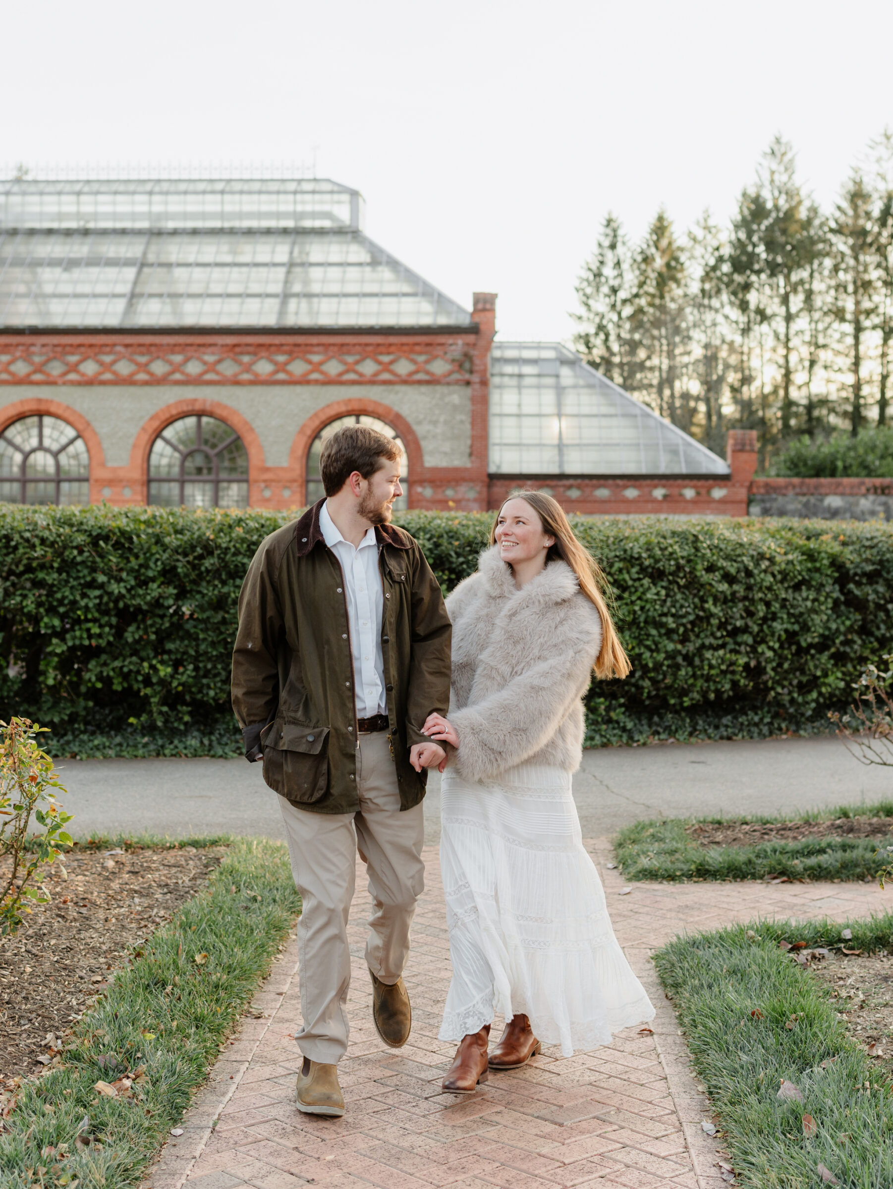Couple walking together and laughing near the Conservatory during a relaxed engagement session