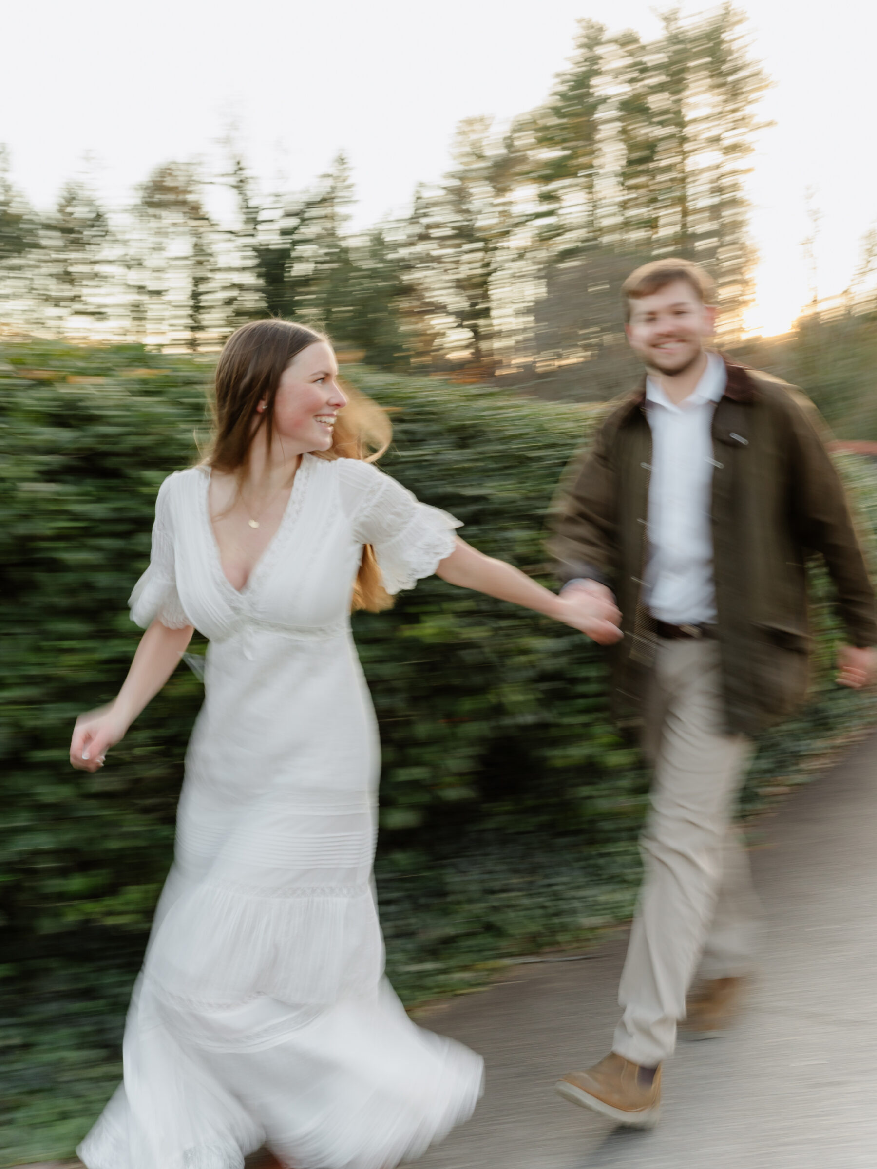 Motion-filled candid of a couple running hand in hand during a joyful engagement moment