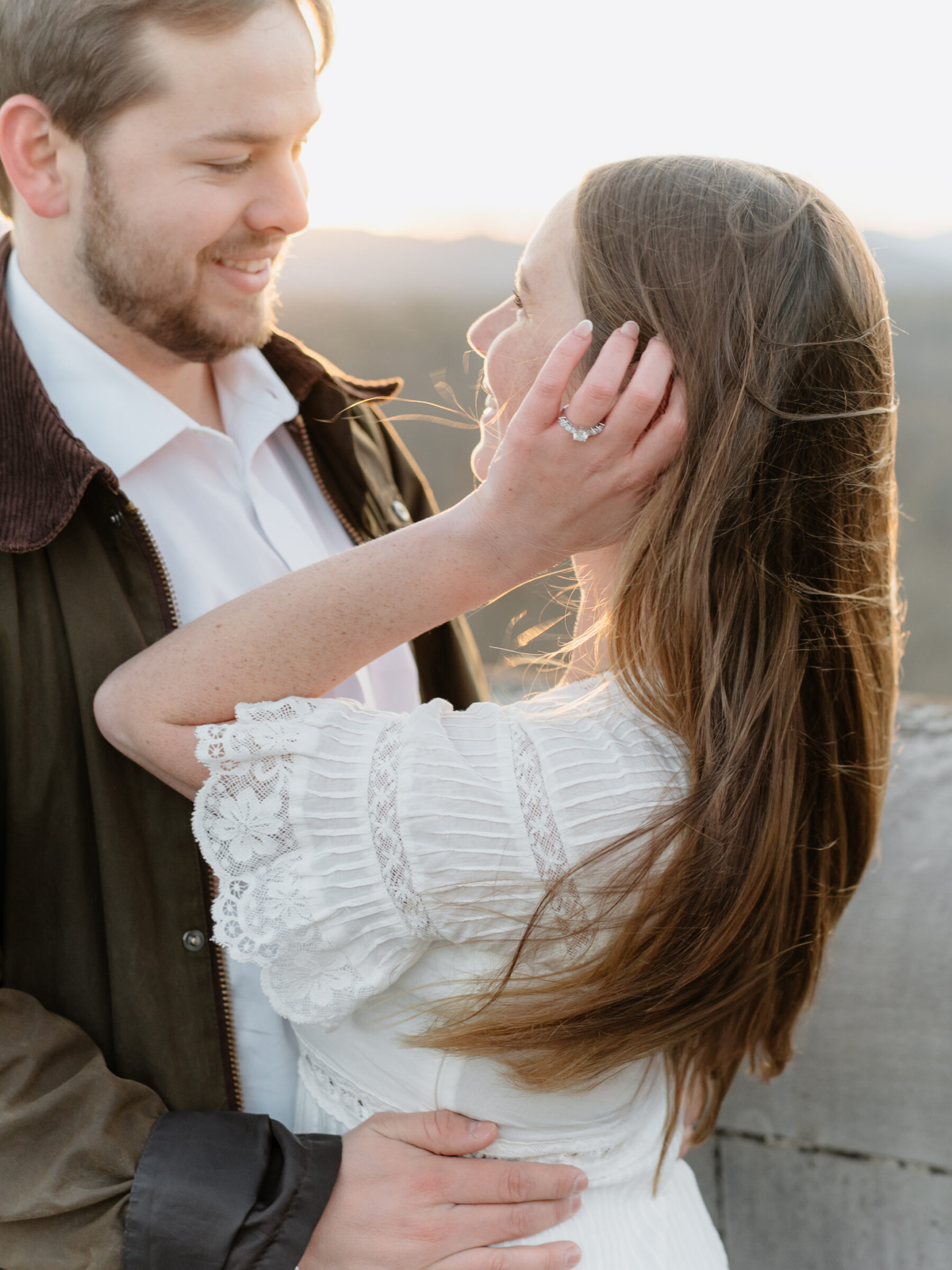 Intimate close-up of a couple sharing a tender moment at sunset, highlighting her engagement ring