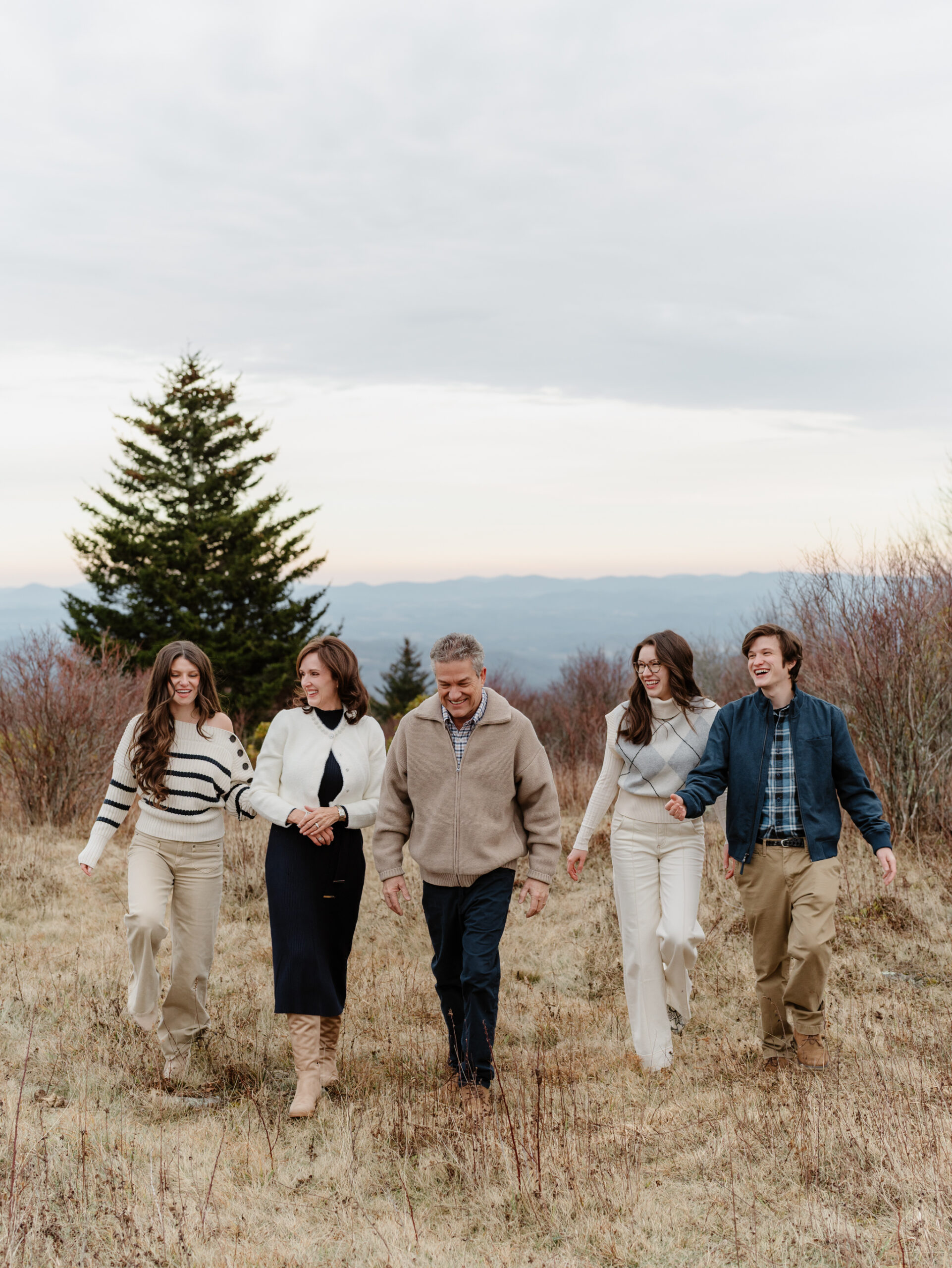 Family walking and laughing together during a late fall family photo session at Grayson Highlands State Park in Southwest Virginia