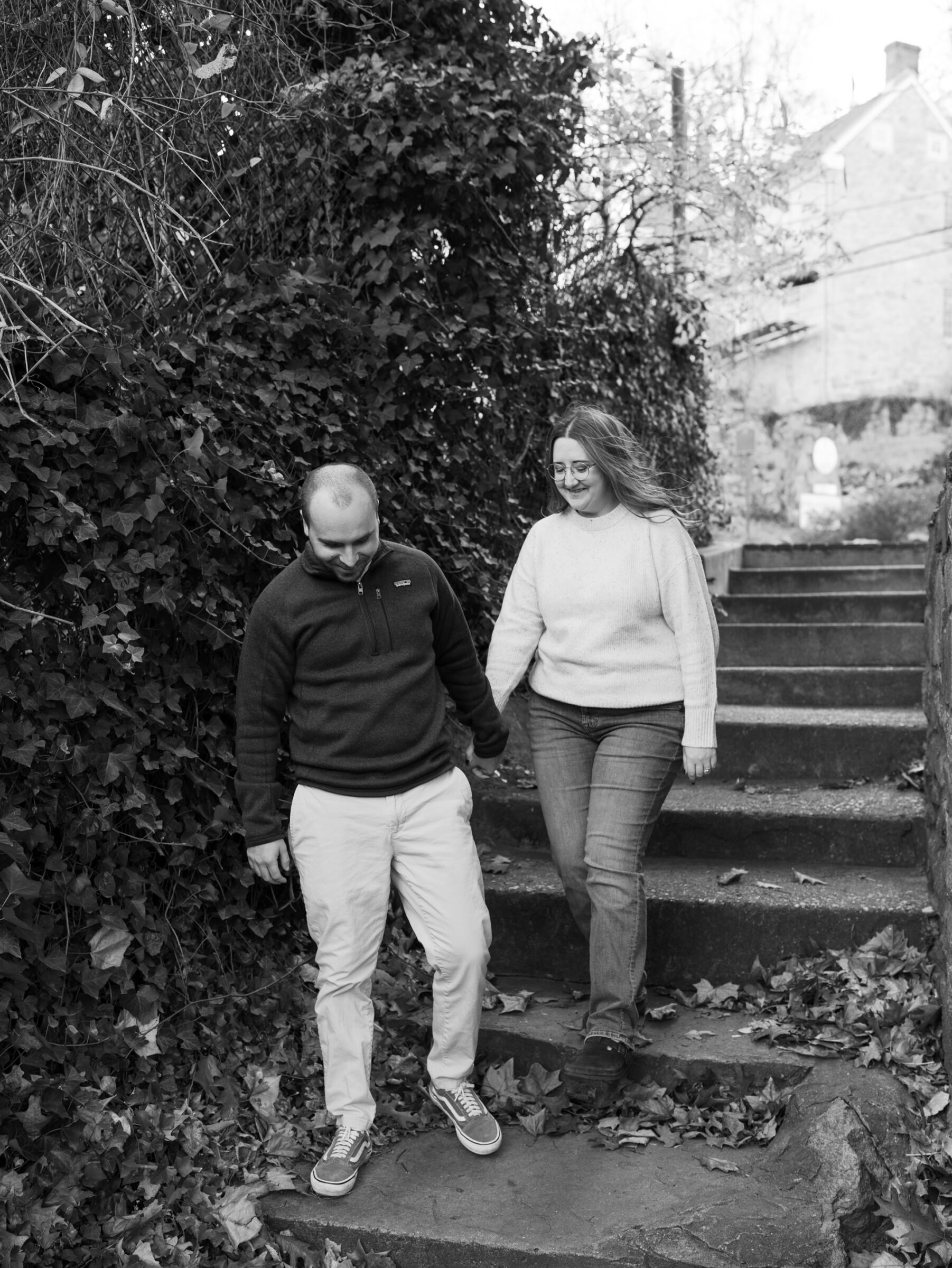 Couple walking down ivy-lined stone steps in Historic Occoquan during their fall engagement session.
