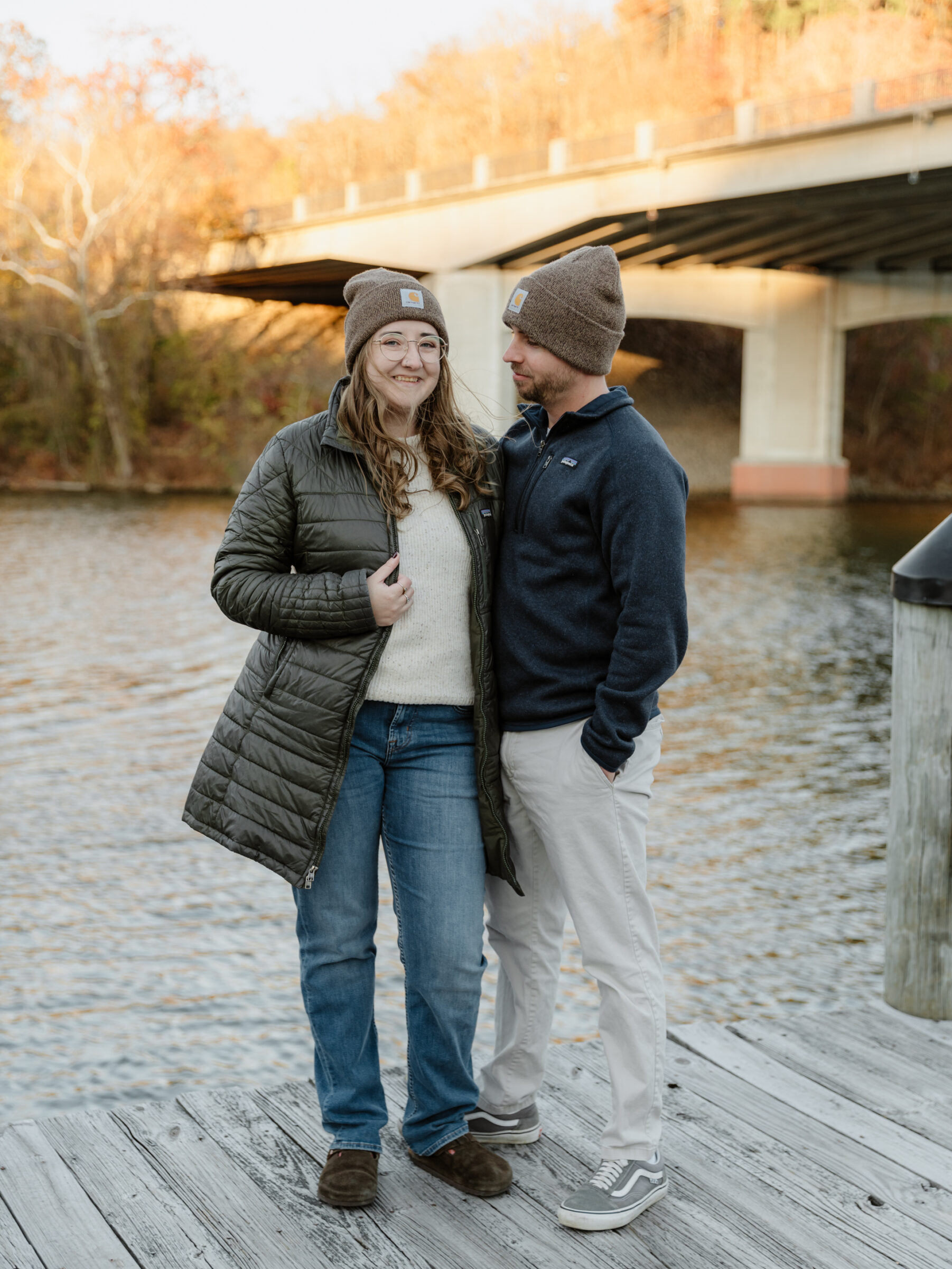 Couple wearing matching knit hats standing together on the Occoquan dock on a chilly fall afternoon.