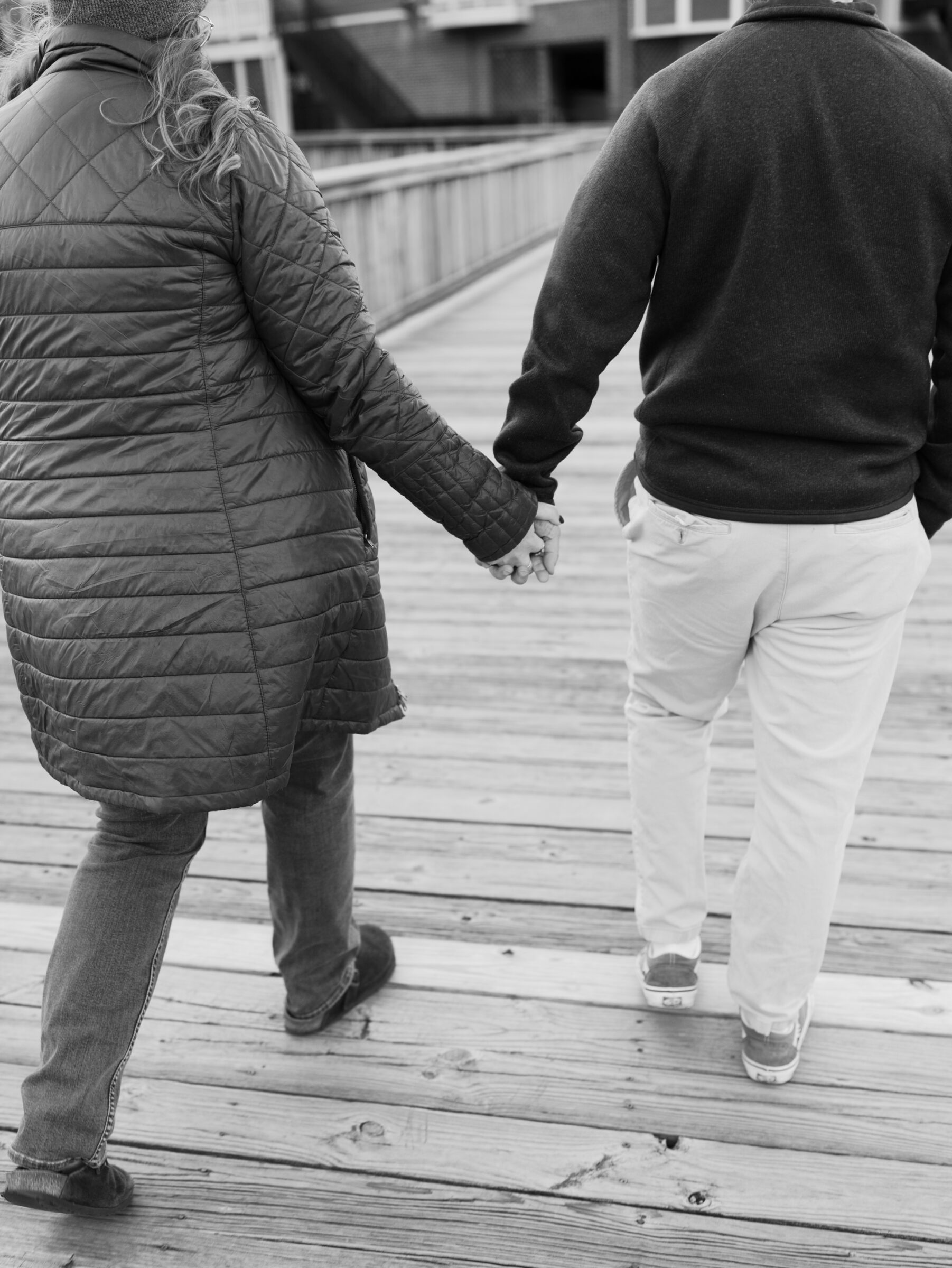 Close-up of a couple holding hands while walking along the wooden dock in Historic Occoquan.