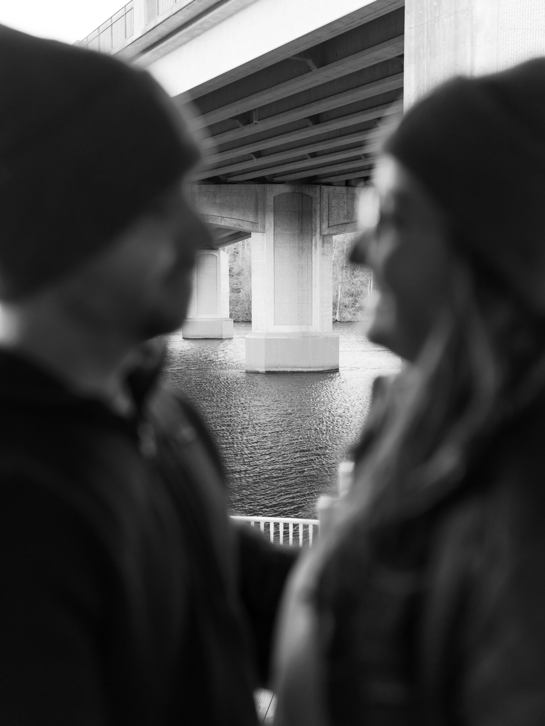 Artistic image showing the Occoquan waterfront and bridge in focus while the couple appears blurred in the foreground.