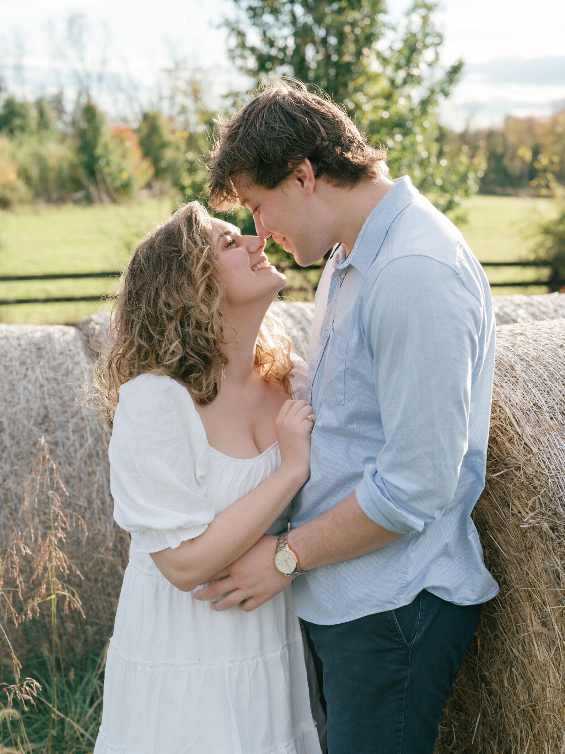 Lovettsville VA Wedding Photographer | Close-up engagement portrait of a couple sharing a quiet moment beside hay bales on their Lovettsville, Virginia property at sunset