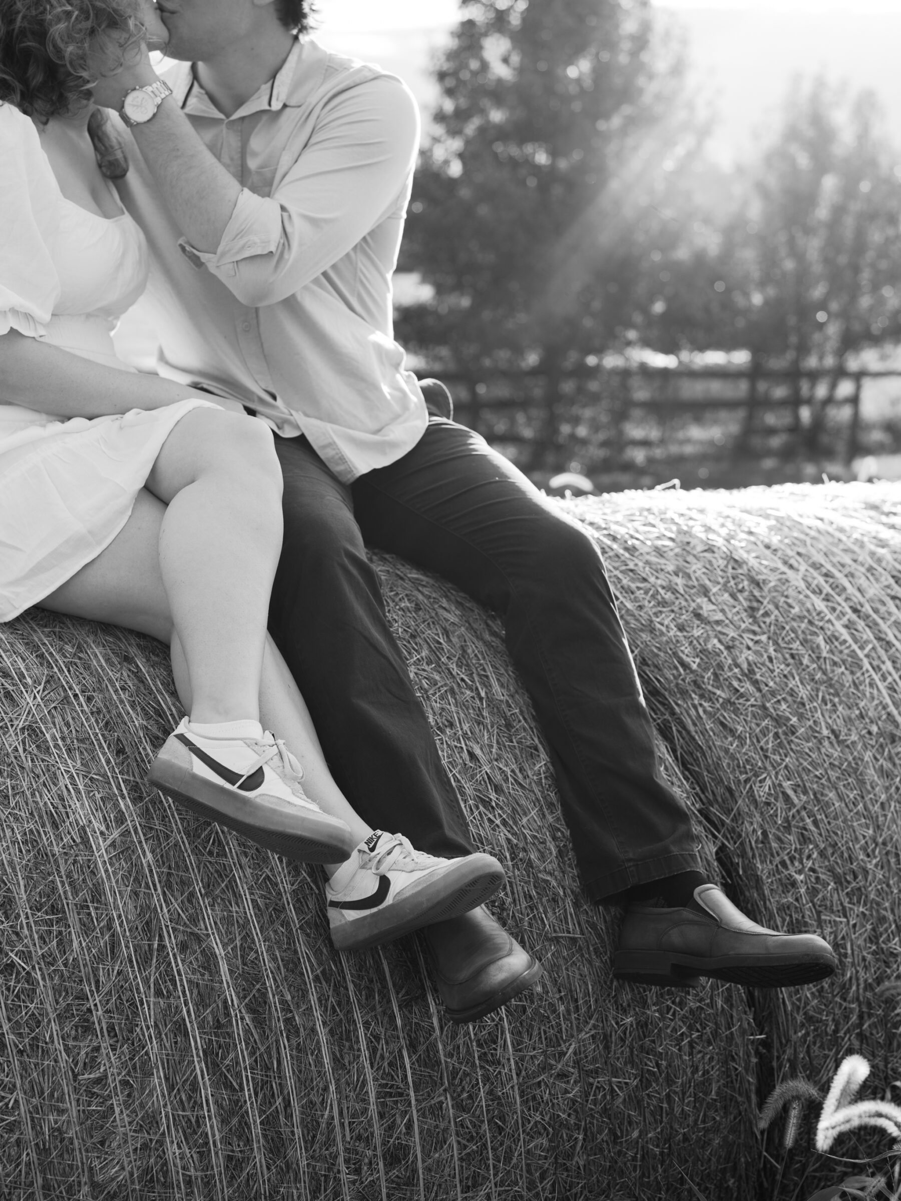 Lovettsville VA Wedding Photographer | Black and white engagement photo of a couple sitting together on hay bales during an at-home session in Lovettsville, Virginia