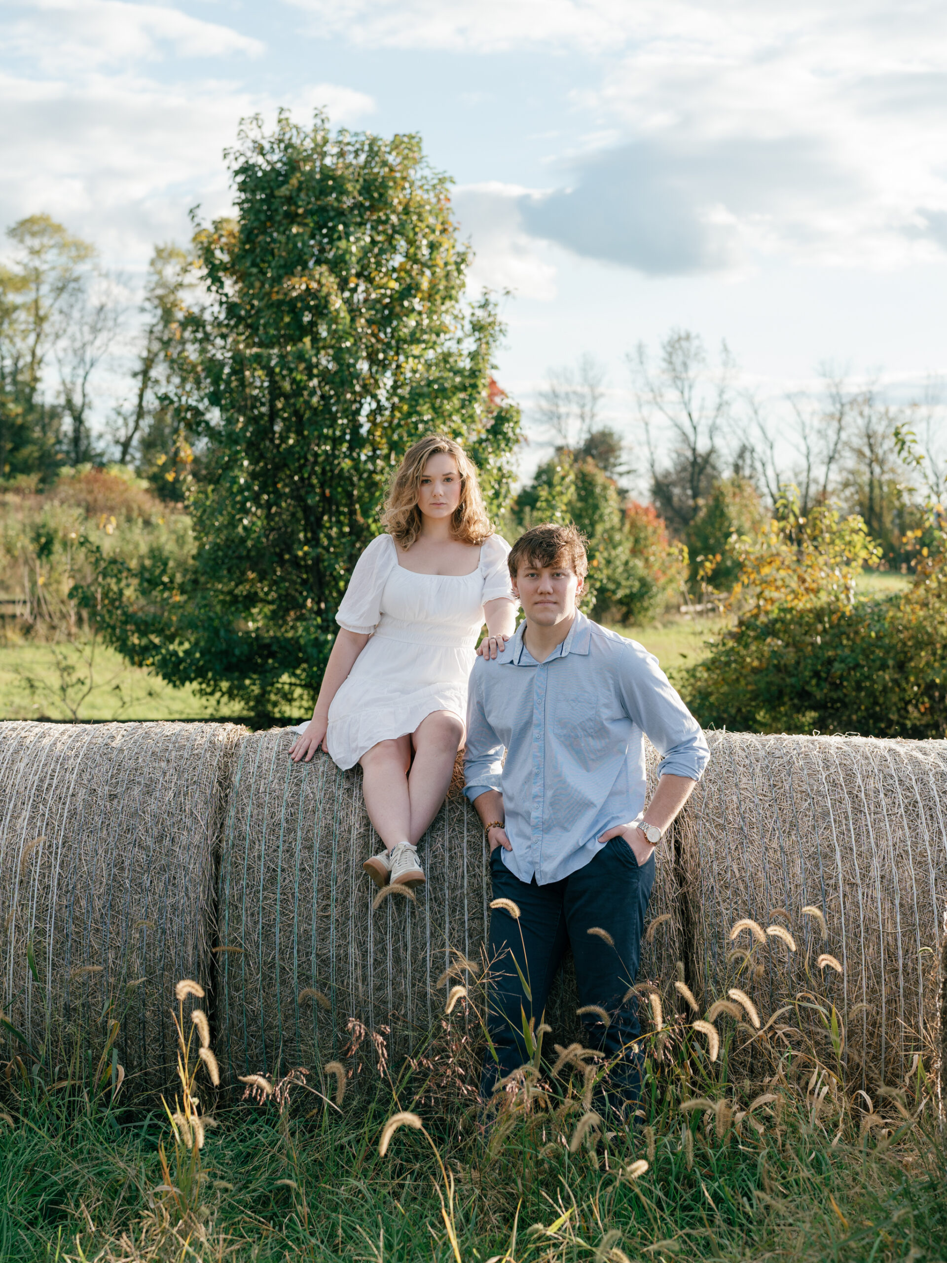 Lovettsville VA Wedding Photographer | Engaged couple posing together on hay bales during an at-home engagement session in Lovettsville, Virginia