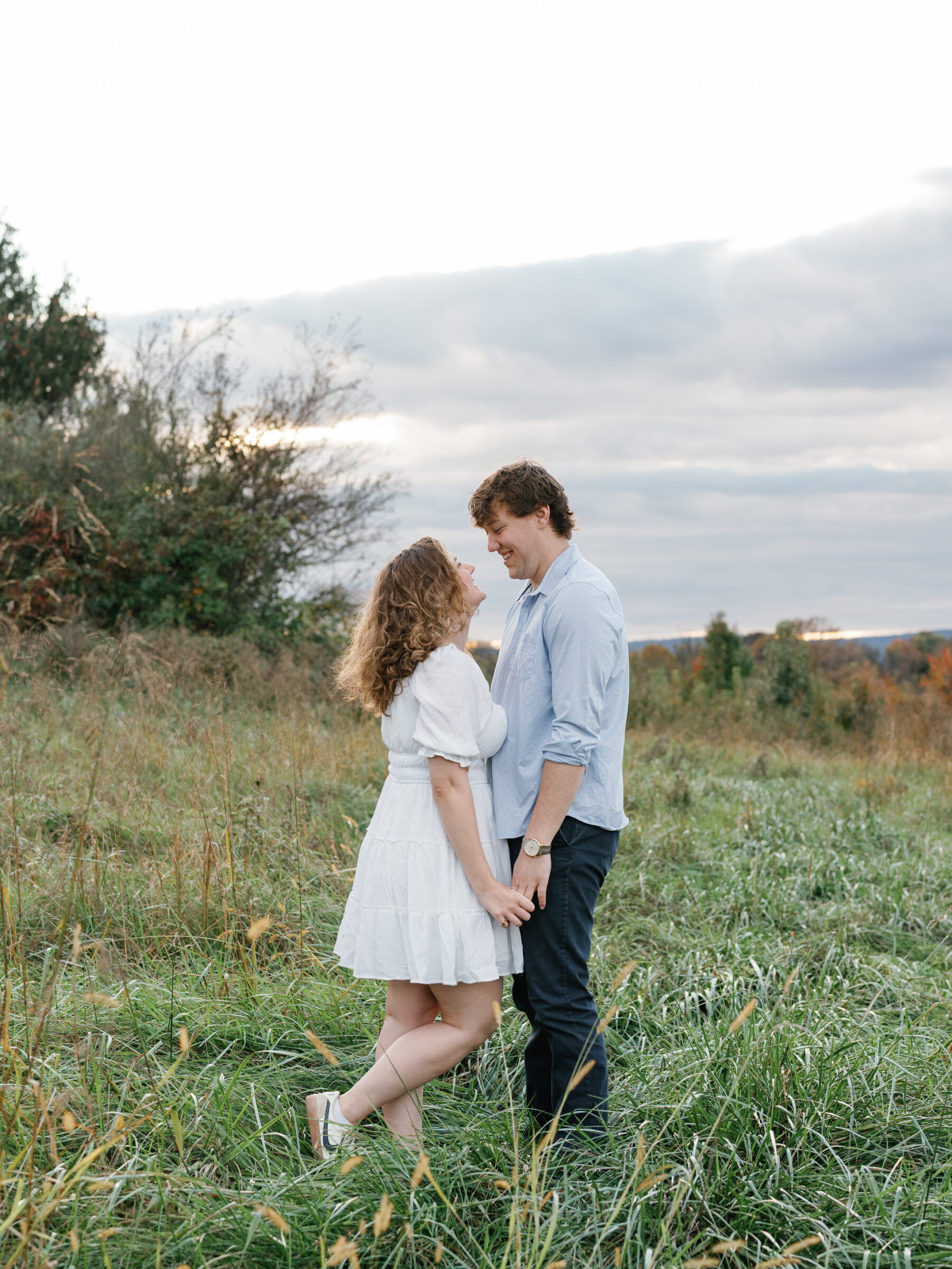 Engaged couple standing together in a grassy field during a relaxed at-home engagement session in Lovettsville, Virginia