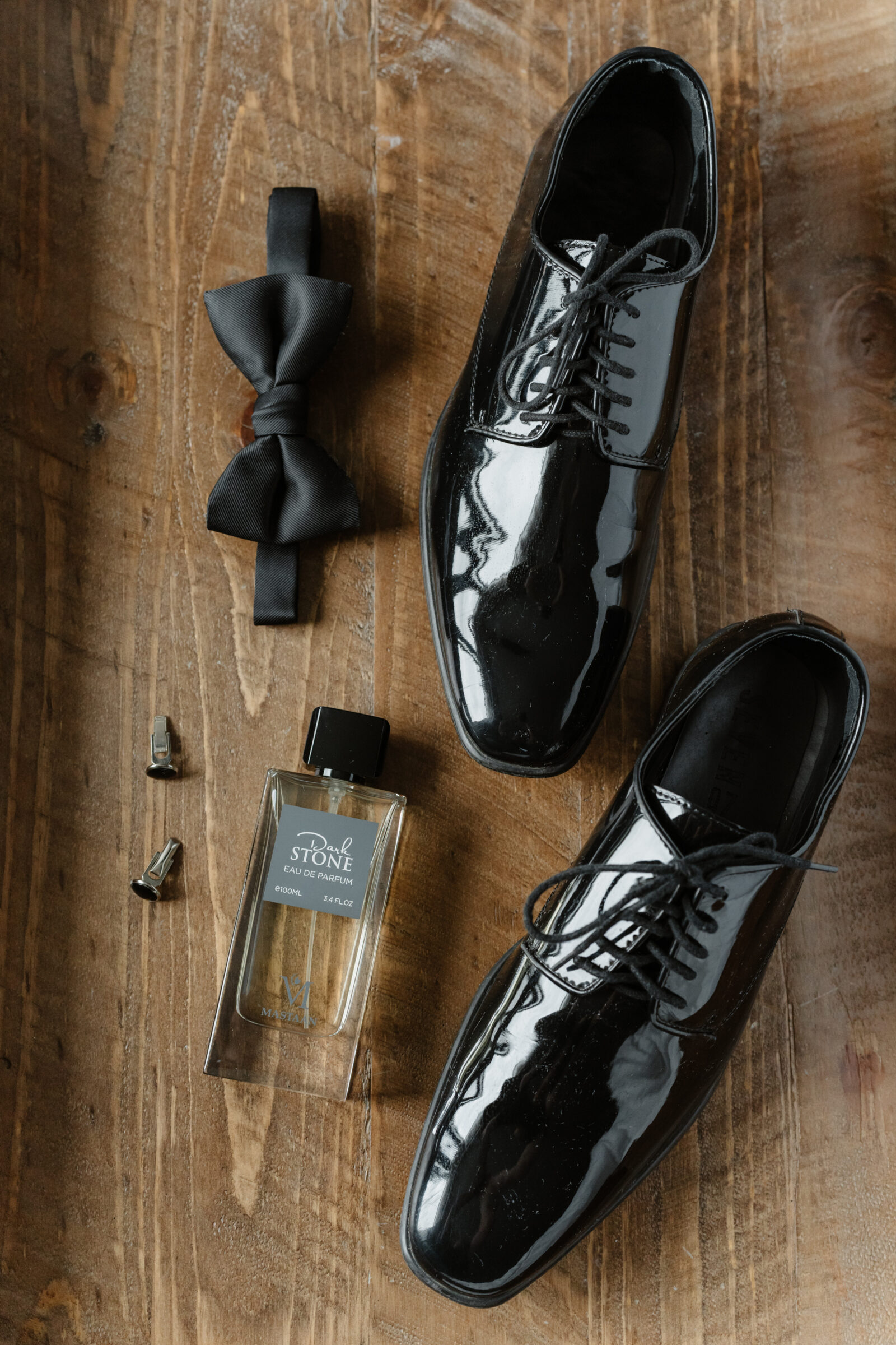 Groom details with black patent leather shoes, bow tie, and cologne at a Northern VA wedding