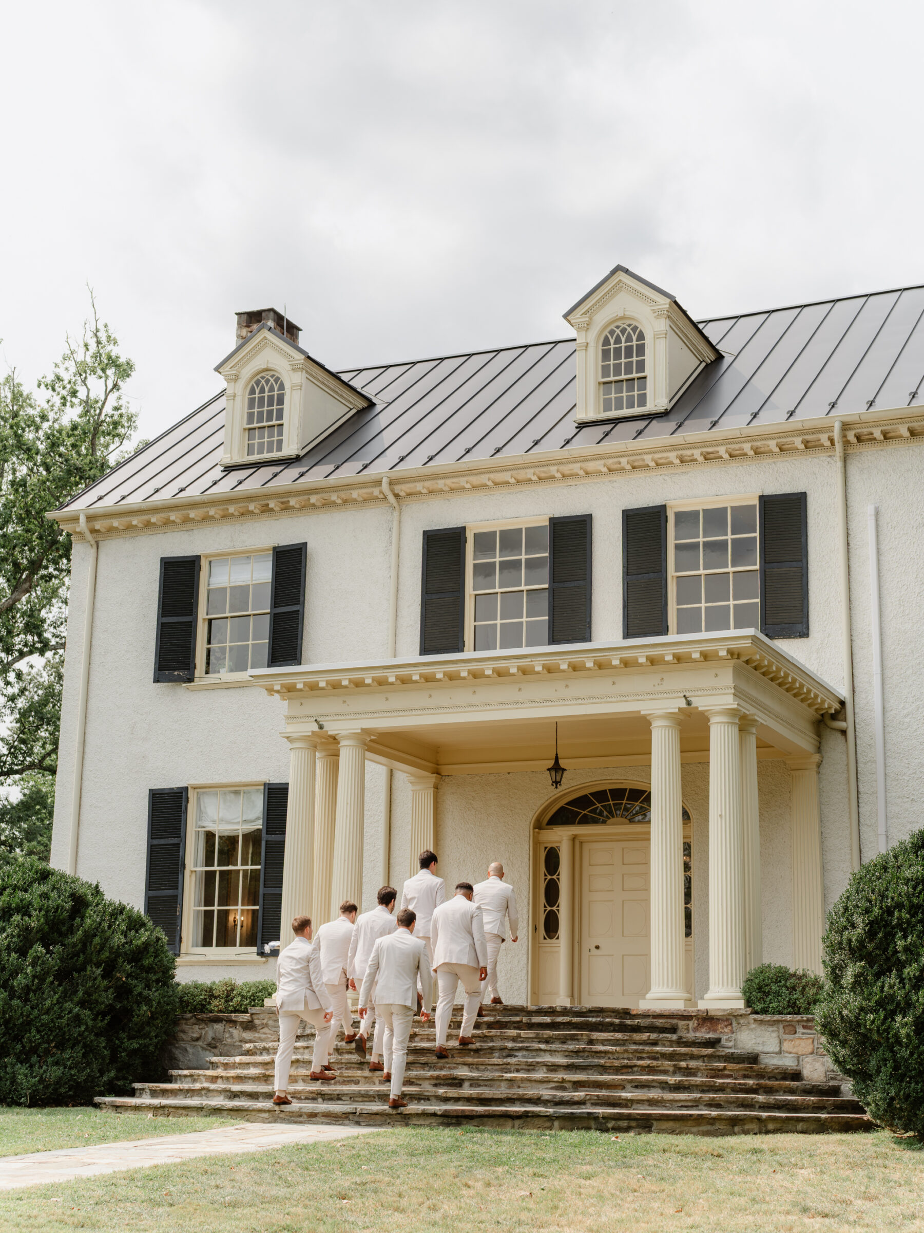 Groomsmen walking up the front steps of Rust Manor House before the wedding ceremony.