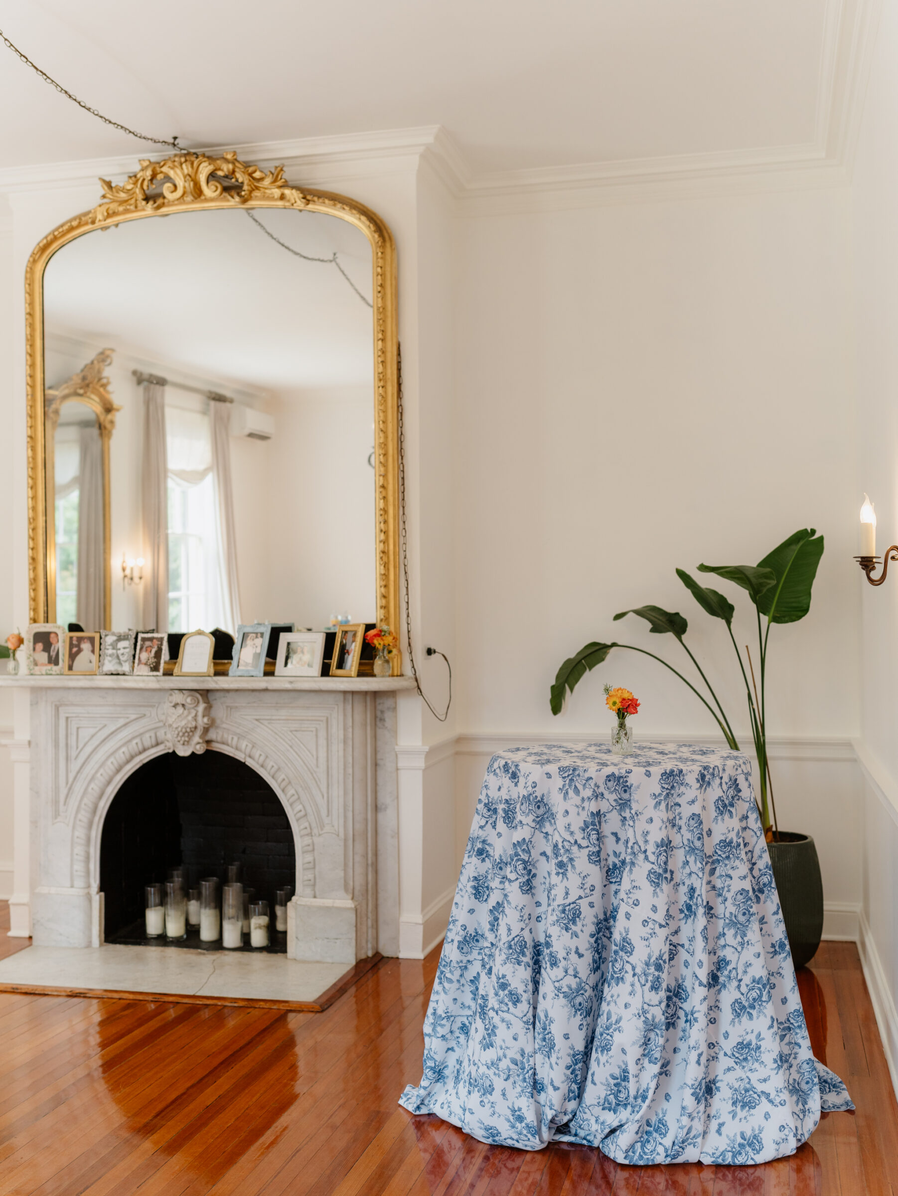 Floral cocktail table setup inside Rust Manor House with a marble fireplace and gold mirror in the background.