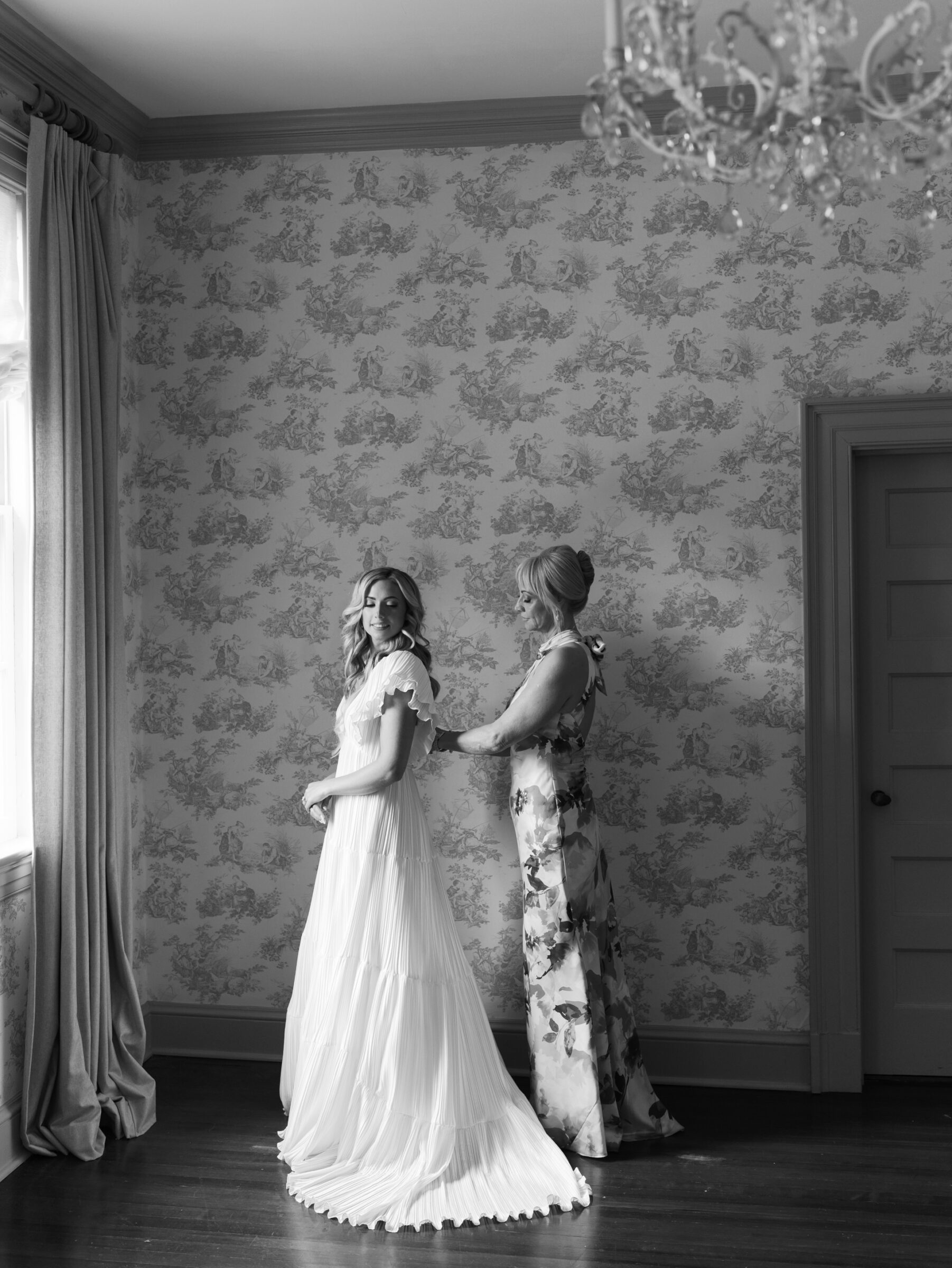 Black and white photo of the bride getting help with her dress in the Rust Manor House bridal suite.