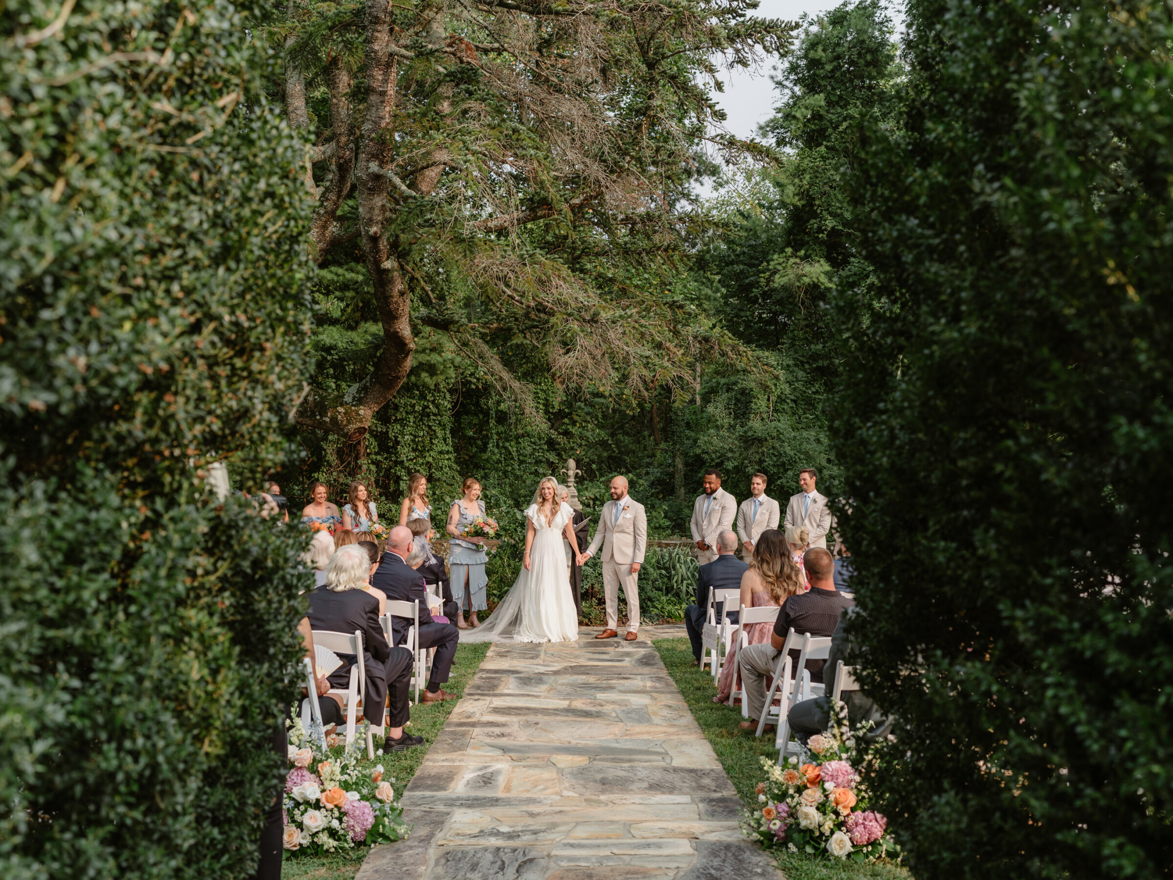 Wide view of the garden ceremony at Rust Manor House as the couple stands at the altar surrounded by bridesmaids, groomsmen, and guests.