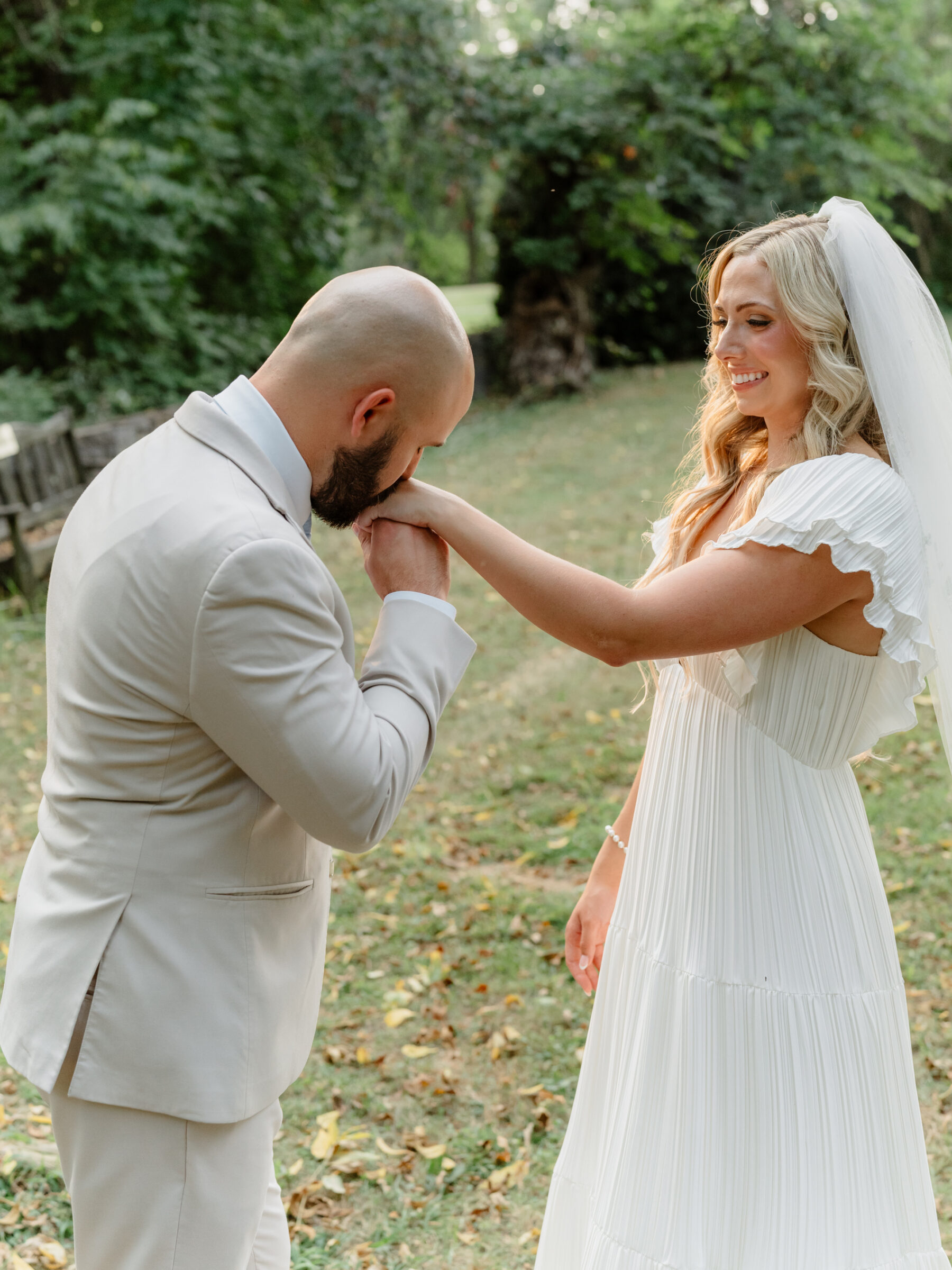 Groom kissing the bride’s hand during a quiet moment in the garden.