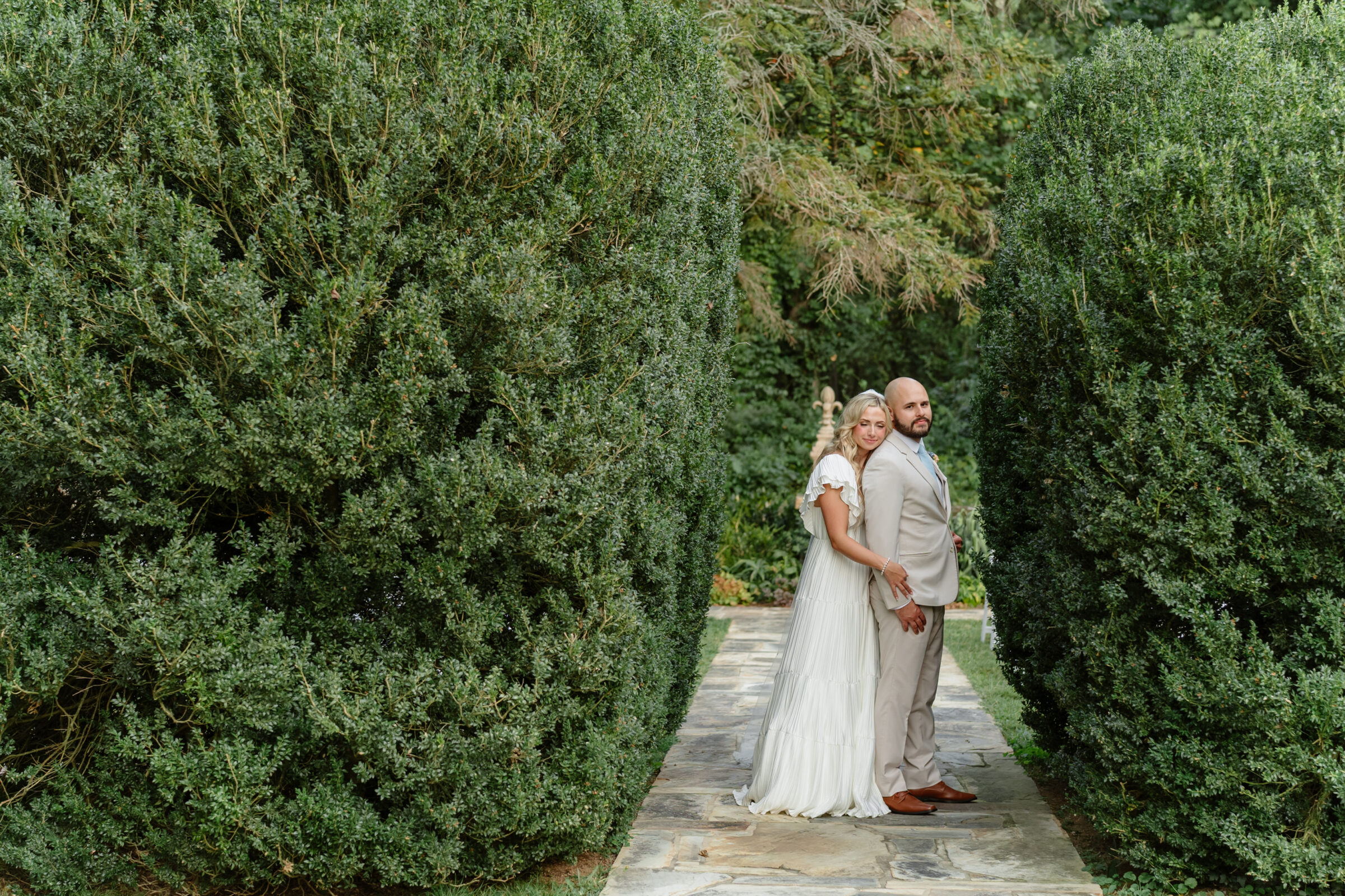 Wedding at Rust Manor House | The couple standing together on the garden path, framed by tall greenery.