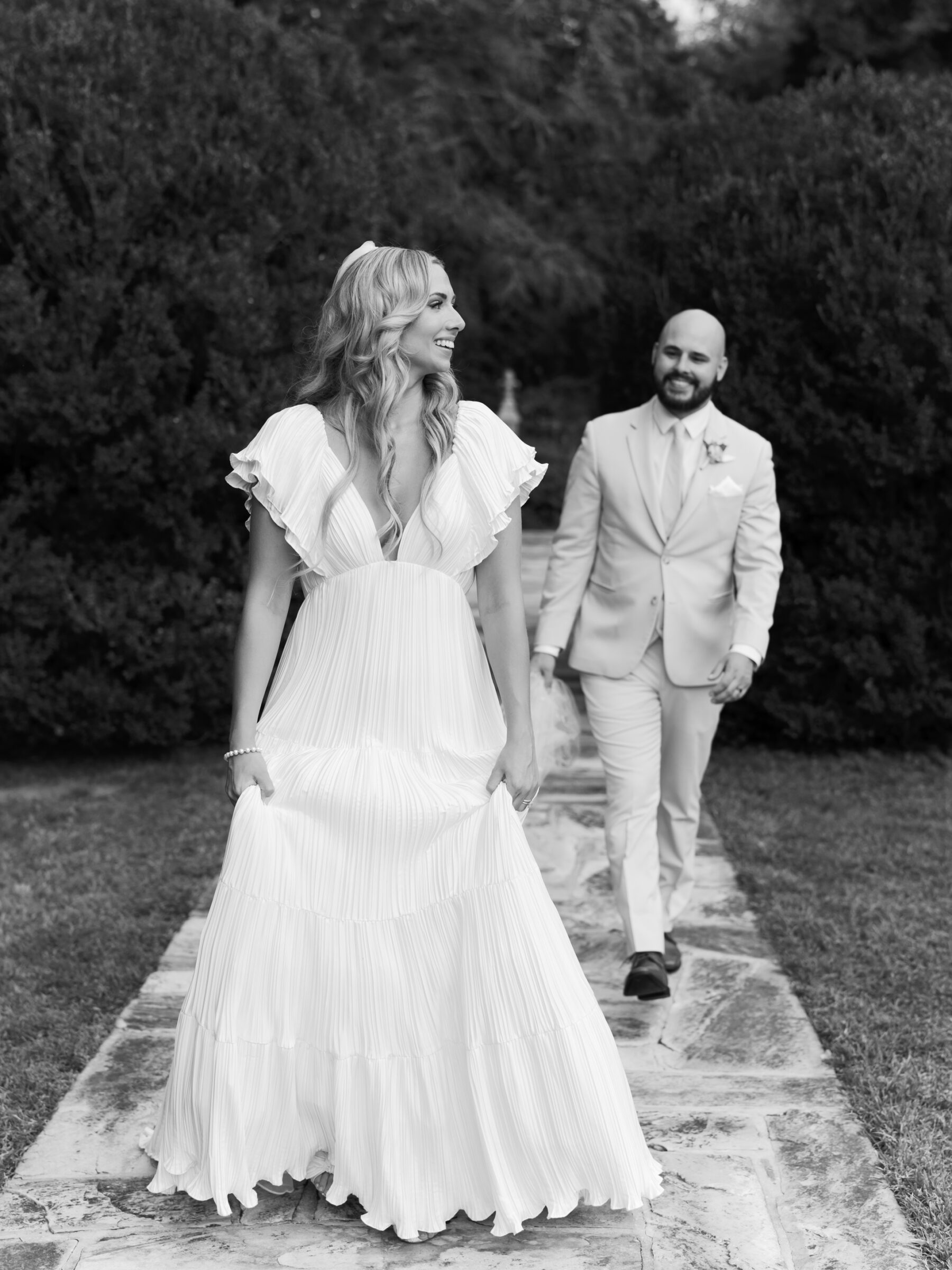 Wedding at Rust Manor House - Leesburg, VA | Bride smiling as she walks ahead of the groom along the stone garden path.