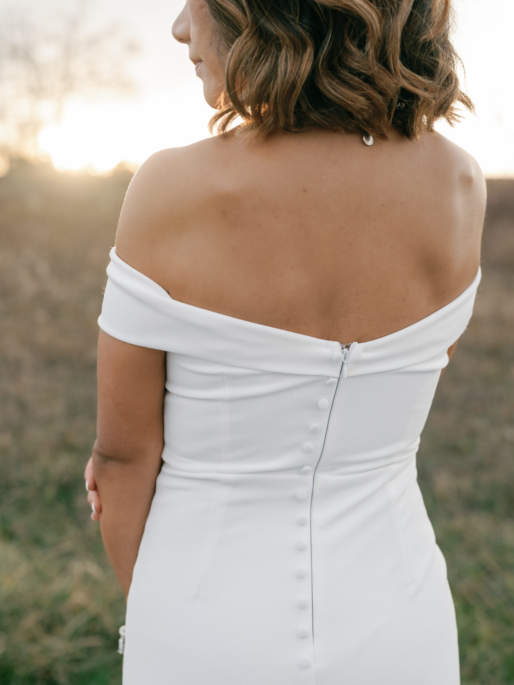 Skyline Drive Virginia Pictures | Back detail of the bride’s off-the-shoulder gown with button accents, captured in soft sunset light at Tanner’s Ridge.