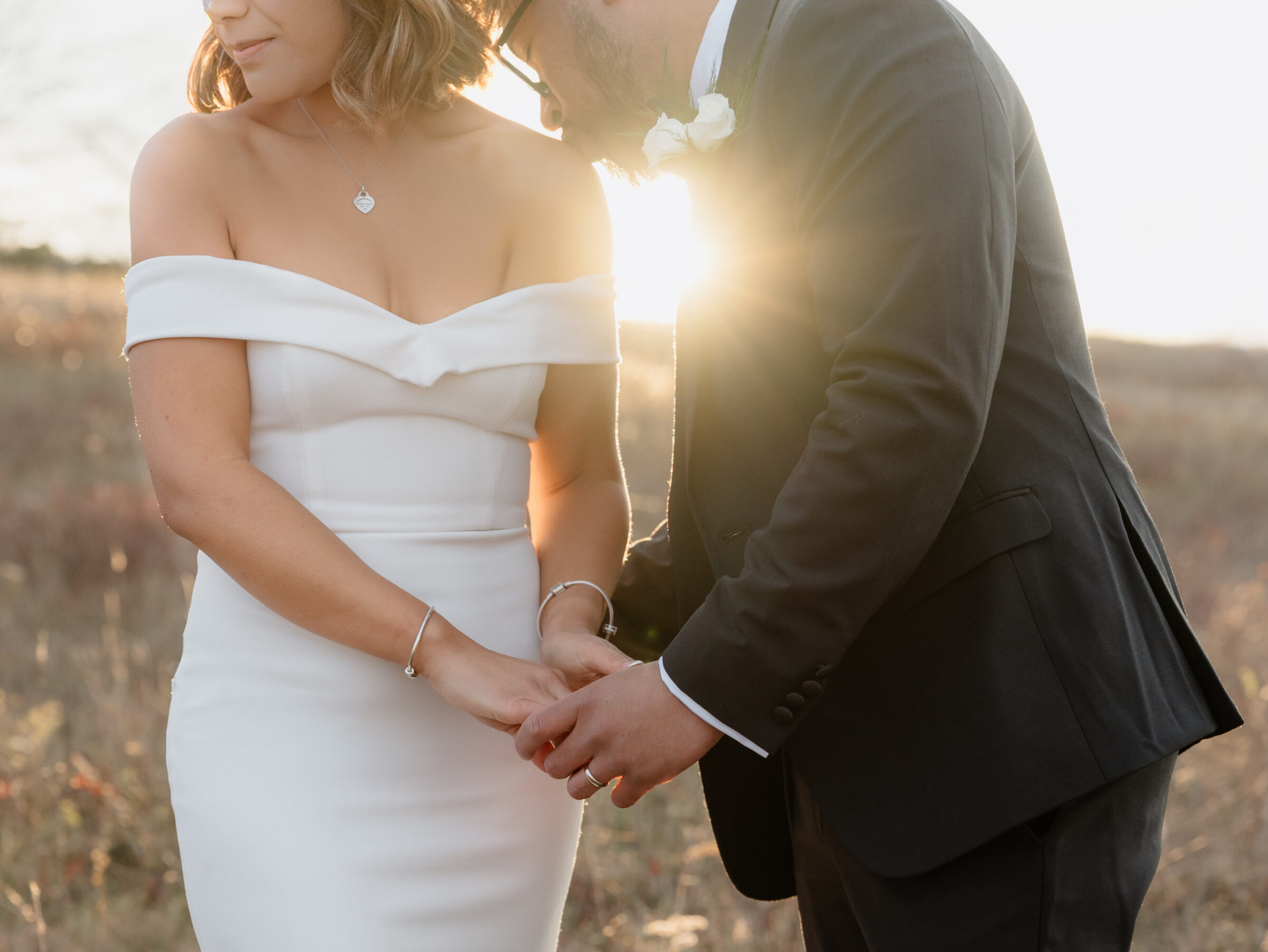 Bride and groom holding hands in an autumn meadow as golden sunlight shines between them during their sunset portraits at Tanner’s Ridge.
