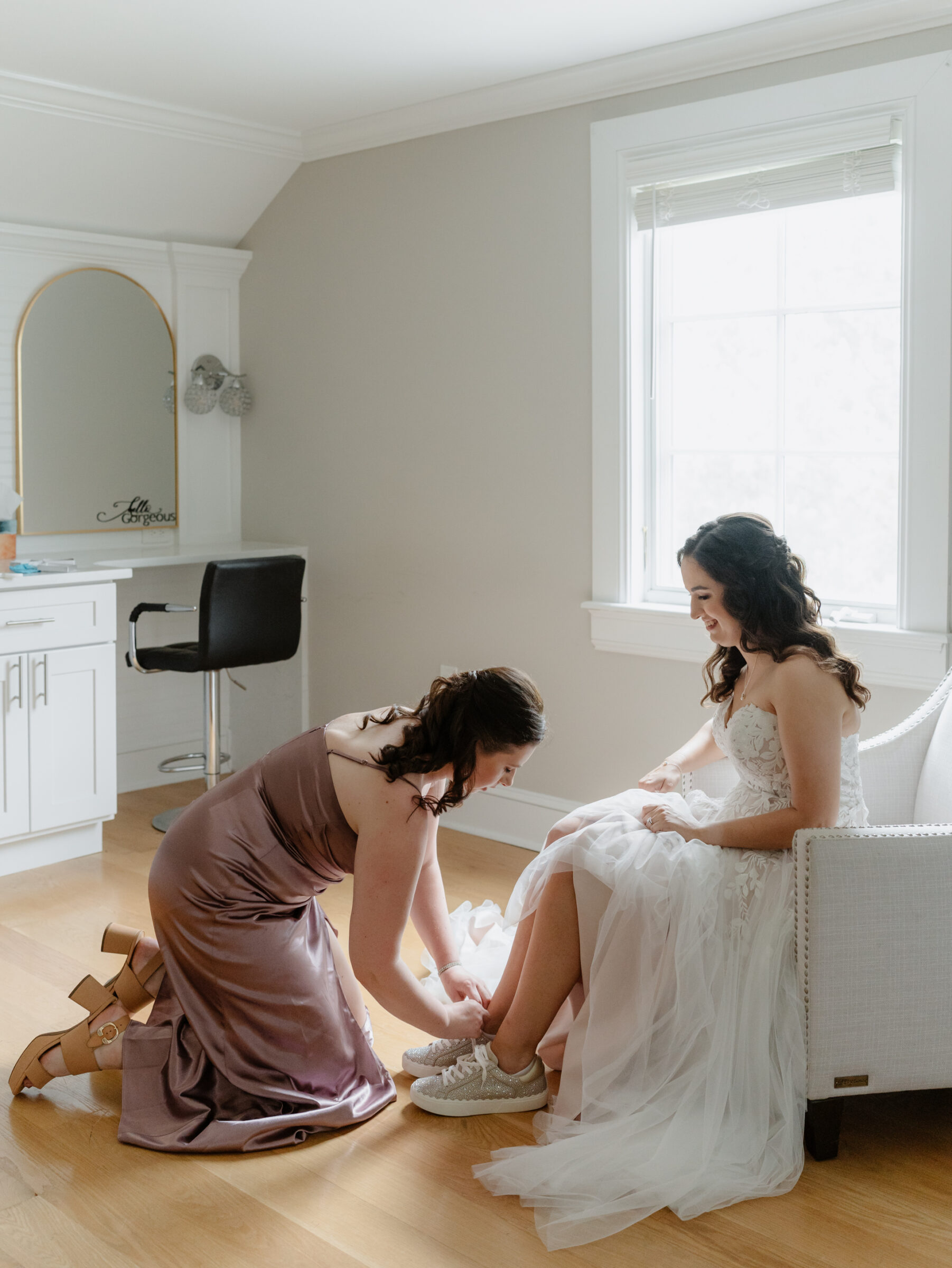 Bridesmaid helping the bride into her shoes during getting-ready moments at a scenic Bluemont VA wedding
